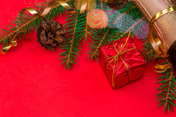 Biglietto natalizio con albero di Natale, champagne, coni, confezione regalo su sfondo rosso. Vista dall'alto con spazio di copia, disposizione piatta. Bellissimo sfondo di Natale - Foto, immagini