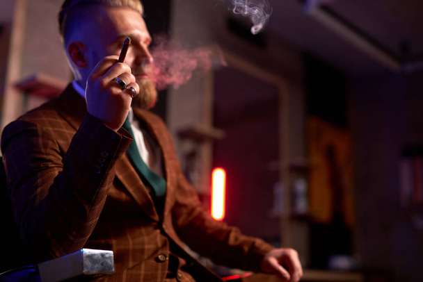portrait of handsome adult man in a formal costume smoking a cigar - Photo, Image