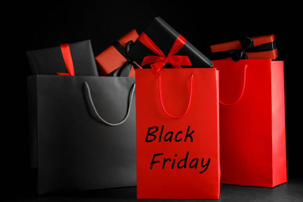 Paper shopping bags and gift boxes on dark background. Black Friday sale - Photo, image