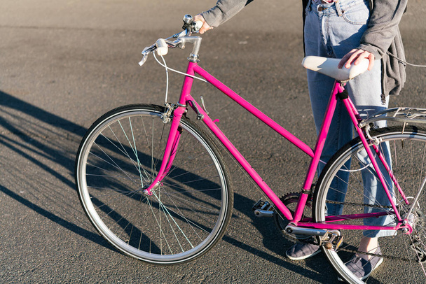 unrecognizable young woman with a pink retro bike at city, concept of active lifestyle and sustainable urban mobility - Foto, afbeelding