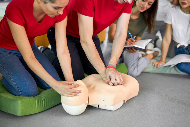 young male practicing CPR on a mannequin in the presence of people - Фото, изображение