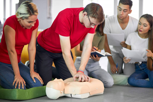 young male practicing CPR on a mannequin in the presence of people - Foto, Bild