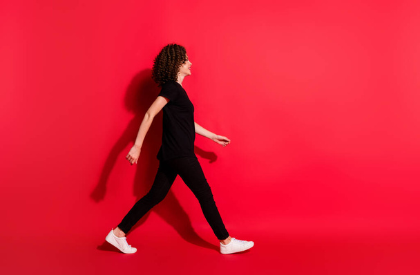 Full body profile side photo of young brown hair girl wear casual outfit go walk empty space isolated over red color background - Foto, immagini