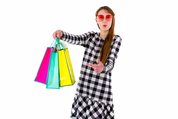 Щаслива дівчина-підліток тримає кольорові сумки для покупок на білому фоні студії.
. - Фото, зображення