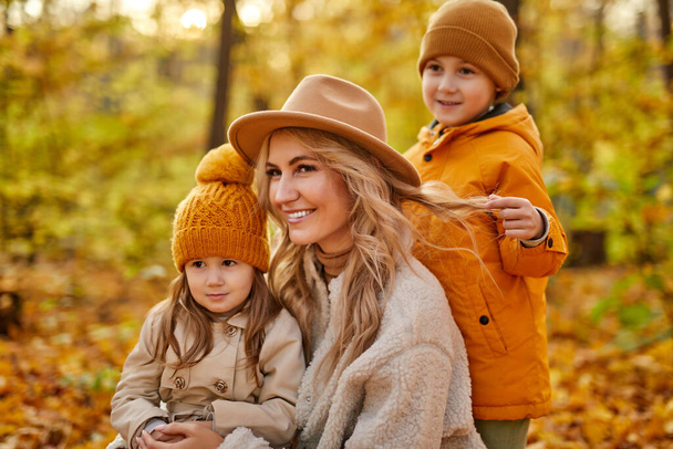 blonde adult woman with children in autumn forest - Fotoğraf, Görsel