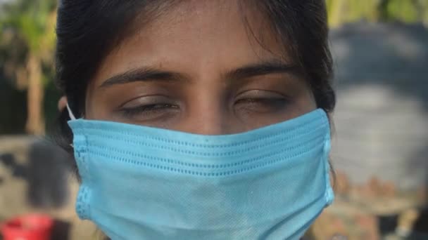 Glimlachend gezicht met masker. Een lachende vrouw met een gezichtsmasker. Close-up Vooraanzicht van een gelukkige Indiase vrouw met een gezichtsmasker lachend en kijkend naar de camera. Gezondheidszorg medische achtergrond India. - Video