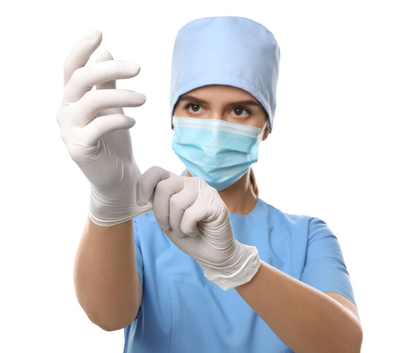Doctor in protective mask and scrubs putting on medical gloves against white background - Fotó, kép