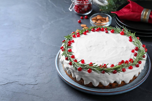Traditional Christmas cake decorated with rosemary and cranberries on dark grey table, space for text - Foto, Bild