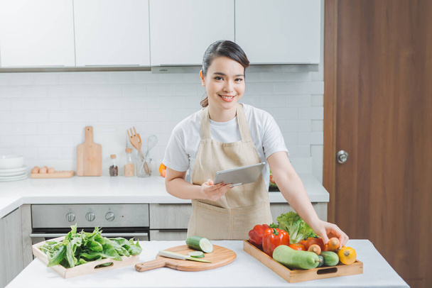 Happy woman looking recipe tablet kitchen reading cooking - Fotografie, Obrázek