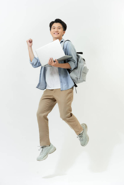 Jumping male Asian programmer with laptop on white background - Фото, зображення