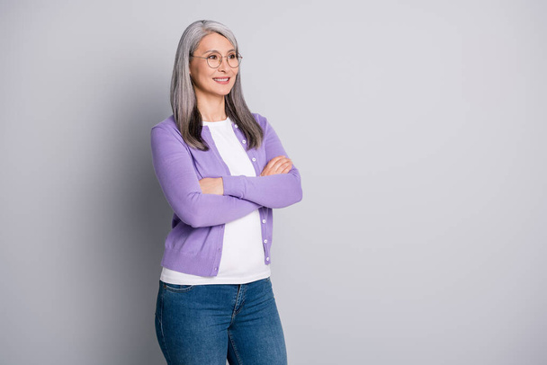 Profile photo of pretty mature lady crossed hands self-assured look empty space wear glasses white shirt purple cardigan denim jeans isolated grey color background - Φωτογραφία, εικόνα