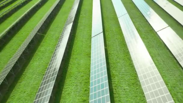 Repülés a napelem mentén a zöld mezőn. Naperőmű zöld energia előállításához. Az ég tükröződése a napelemben - Felvétel, videó