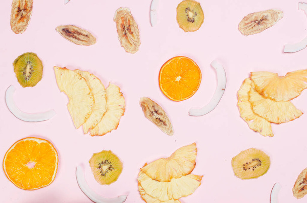 Dried slices of different fruits chips scattered on pink background. Assorted Fruit chips. Healthy eating concept, snack, no sugar. Top view, copy space.  - 写真・画像