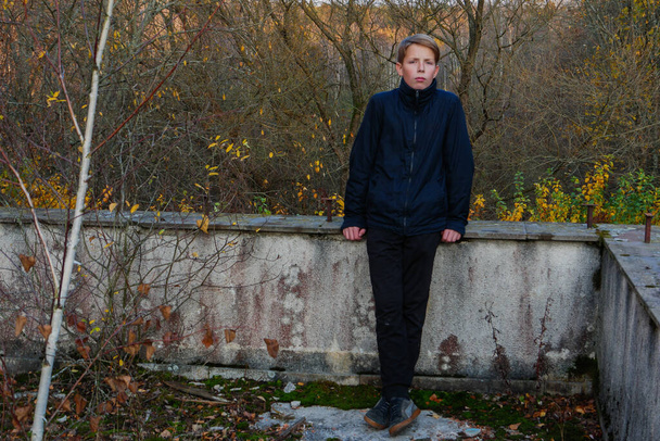 boy near the concrete fence against the background of the forest. - Foto, afbeelding