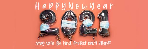 Balloon Bunting for celebration of New Year 2021 made from Silver Number Balloons with protective face masks on pink background. Stay safe, be kind, protect each other, concept of New Reality - Photo, Image