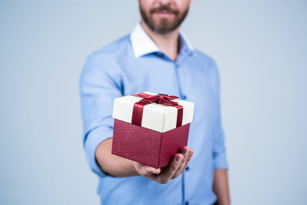 Man cropped view gift present box pack tied with red ribbon selective focus, gifting - Fotó, kép