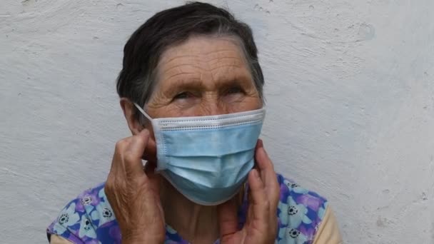 Senior vrouw neemt af en vouwt wegwerpmasker van gerimpeld gezicht - Video