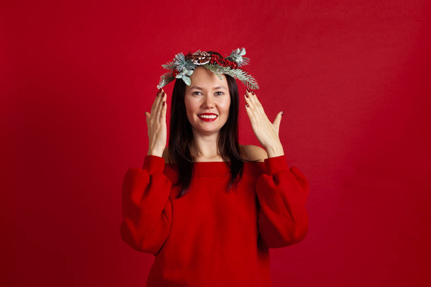 portrait of a happy smiling Asian young woman opening or closing her eyes, waiting for a gift, on a red background - Foto, afbeelding