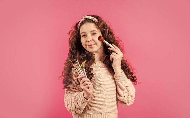 beautiful kid play cosmetics. Beauty salon. happy childhood. fashion and beauty. retro girl put natural makeup with brush. hair and skin care. small girl wear vintage headband - Foto, Imagen