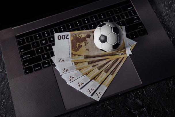 Ballon de football et billets en euros sur un clavier. Sport, jeu, concept de pari - Photo, image