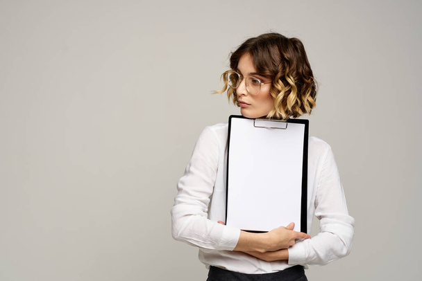 Zakelijke vrouw in een licht shirt en een map met documenten in handen bijgesneden weergave van het werk - Foto, afbeelding