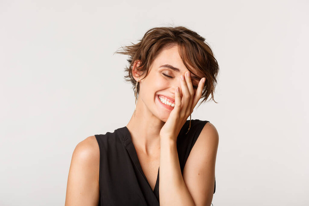 Close-up of carefree beautiful woman, close eyes and laughing from happiness, standing over white background - Foto, Bild