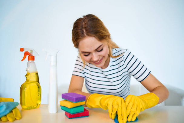 Masadaki kadın temizlik malzemelerini yıkıyor. - Fotoğraf, Görsel