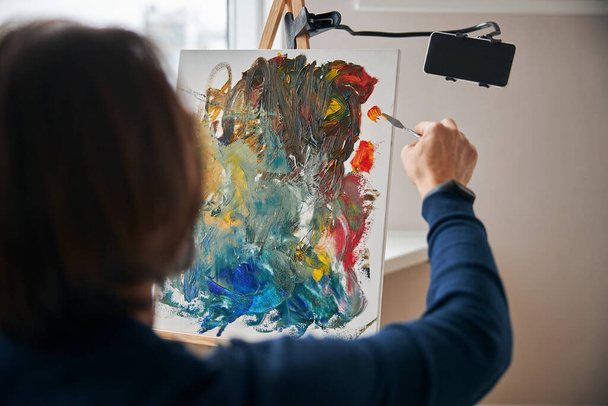 Artista enfocado con paleta-cuchillo pintura sobre lienzo - Foto, Imagen