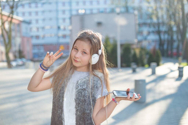 Ευτυχισμένο κορίτσι με ακουστικά ακούει μουσική από το τηλέφωνο - Φωτογραφία, εικόνα