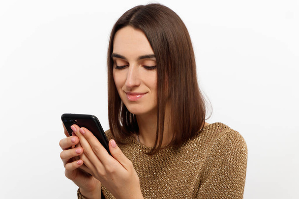 Front portrait of young smiling woman using mobile phone against white background - Foto, Bild