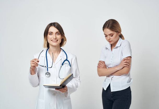 Nővérke dokumentumokkal a kezében és női beteg könnyű háttérrel - Fotó, kép