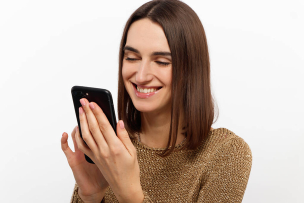 Front portrait of young smiling woman using mobile phone against white background - Foto, Imagem