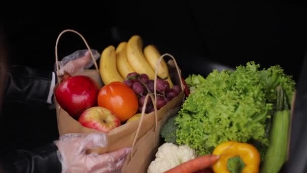 車のトランク内のエコパッケージ内の食料品のクローズアップ。スーパーでの出荷後に野菜や果物を梱包する女性の手 - 映像、動画