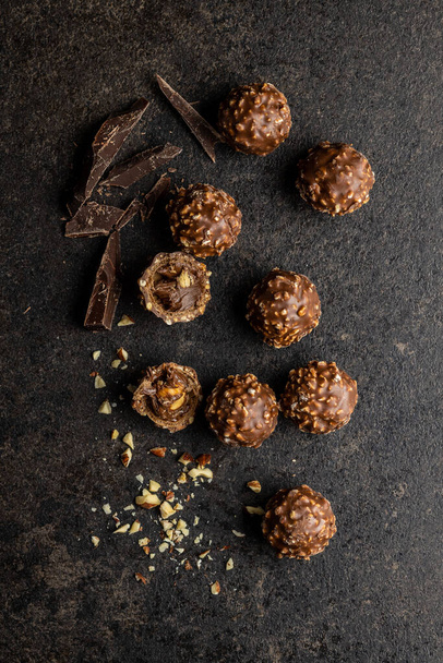 Sweet chocolate truffles. Tasty belgian pralines balls with dark chocolate on black table. Top view. - Foto, afbeelding
