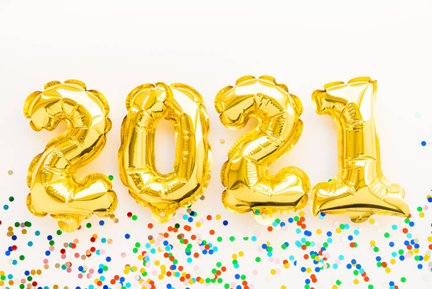 Happy New year 2021 celebration. Gold foil balloons numeral 2021 and confetti on white background. Flat lay - Foto, Imagen