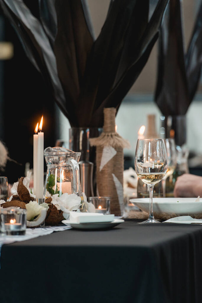 Mesas servidas para banquete de bodas con platos restaurante. Decoración de flores frescas, cocos y hojas oscuras - Foto, Imagen
