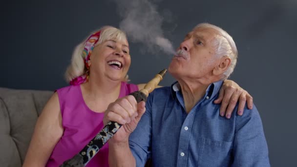 Starší pár kouří doma hašiš. Starší babička a dědeček se baví, relaxují - Záběry, video