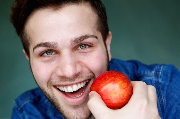 Улыбающийся мужчина держит красное яблоко
 - Фото, изображение