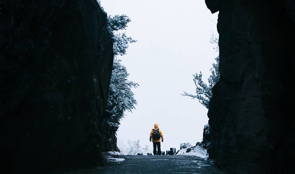Névtelen személy sárga kabátban egy barlangban. Utazó személy a téli táj hó. Karácsonyi és téli ünnepek koncepciója. Hátizsák. - Fotó, kép