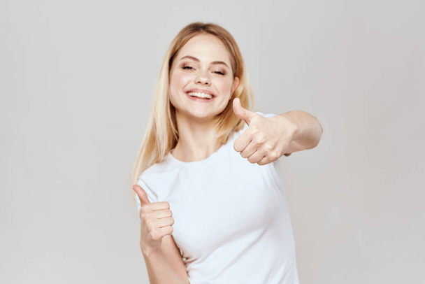 Nette blonde weiße T-Shirt-Geste mit den Händen Lifestyle Licht Hintergrund - Foto, Bild