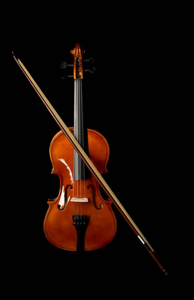Brown wooden fiddle or violin, classic musical instrument, with bow isolated over black background, flat lay top view from above - Zdjęcie, obraz