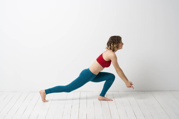vrouw in leggings is bezig met gymnastiek in een lichte kamer slanke figuur fitness sport - Foto, afbeelding