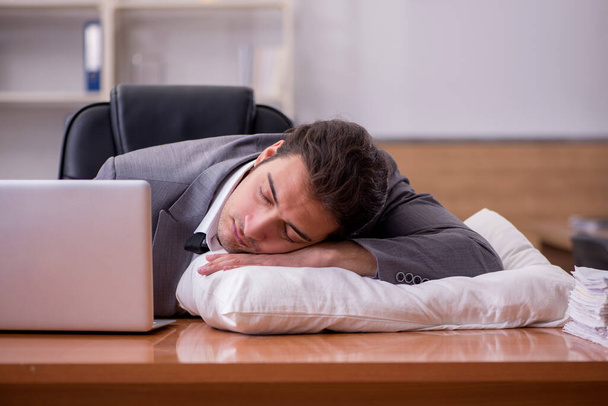 Giovane dipendente maschio che dorme sul posto di lavoro - Foto, immagini