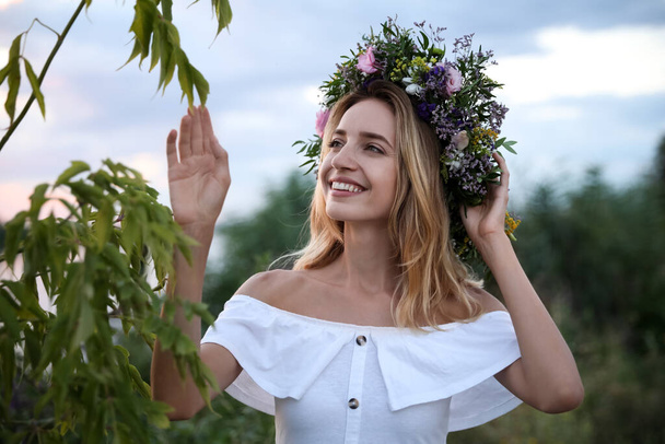 Młoda kobieta nosi wieniec z pięknych kwiatów na świeżym powietrzu - Zdjęcie, obraz