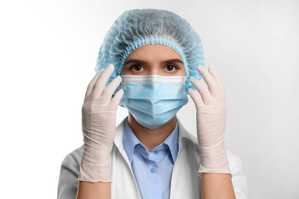 Doctor with medical gloves, mask and cap on white background - Fotografie, Obrázek