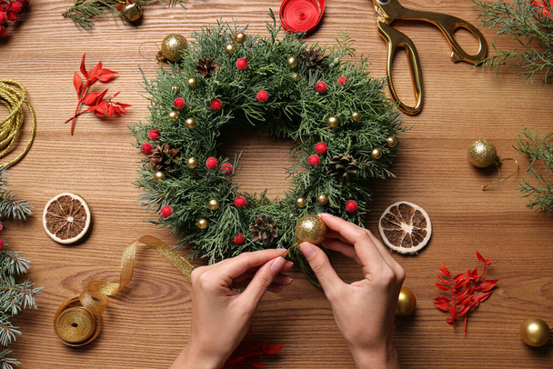 Florist making beautiful Christmas wreath at wooden table, top view - Photo, image