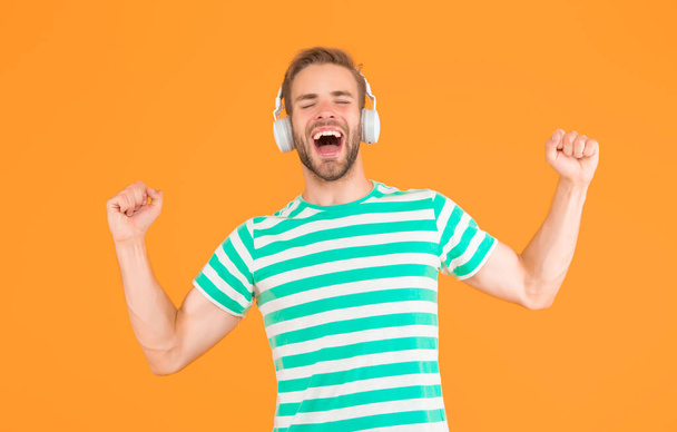 Music makes me happy. Happy man listen to music yellow background. Handsome guy enjoy melody playing in headphones. Happy music. Pleasure and joy. Fun and entertainment. Happy new mix. Super hit - Photo, Image