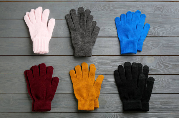 Set of stylish gloves on grey wooden background, flat lay - Foto, imagen