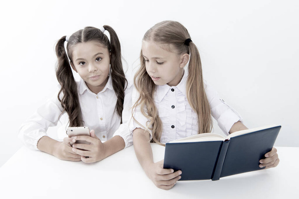 Innovation and archaism concept. Children read paper book and electronic mobile device using innovation and archaism - Valokuva, kuva