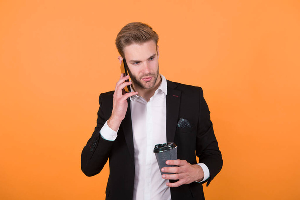 Reporting news. Man drink coffee speak phone yellow background. Drink coffee. Reasons entrepreneurs drink coffee. Coffee break concept. Relax and pleasure. Concentrated on listening information - Valokuva, kuva